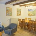 Wohn- und Essbereich mit Holzdecke, Sofa, Stuhl und Wandbildern.