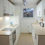 Küche mit weißen Schränken, Holzwerkzeug und Fenster.