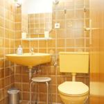 Badezimmer mit gelbem Waschbecken, Toilette und Spiegel an der Wand.