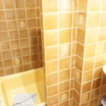 Bad mit Dusche, Waschbecken und gelben Fliesen