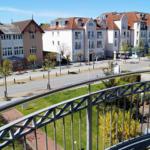 Blick von Balkon auf Straße mit Häusern und Grünflächen