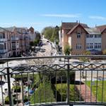 Balkon mit Blick auf eine Straße mit Häusern und Grünflächen.