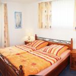 Schlafzimmer mit Doppelbett, zwei Nachttischen und Fenstern mit Vorhängen.