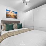 Schlafzimmer mit Bett, Kleiderschrank und Wandbild