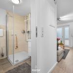 Badezimmer mit Dusche und Toilette. Wohnbereich mit TV und Sitzgelegenheit.