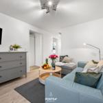 Wohnzimmer mit Sofa, Couchtisch und Fernseher an der Wand.