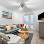 Wohnzimmer mit Sofa, Couchtisch und Fernseher an der Wand.