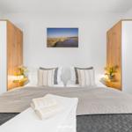 Schlafzimmer mit Bett, Kissen, Decke und Wandbild.