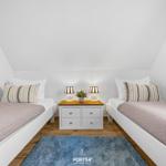 Zwei Betten mit Streifenkissen und Nachttisch mit Lampen.