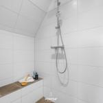 Duschkabine mit Duschbrause, Handtuch und Pflegeprodukten auf Sitzbank.