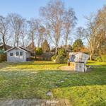 Hinterhof mit Gartenhaus und Strandkorb auf Rasenfläche.