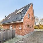 Rotes Backsteinhaus mit schwarzem Dach und Gartenbereich.