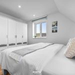 Schlafzimmer mit Bett, Kleiderschrank und Fenster mit Blick.