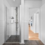 Badezimmer mit Dusche, Heizkörper und Blick in den Flur.