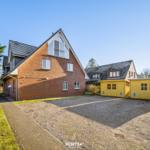 Rotes Backsteingebäude mit Dachgauben und gelben Garagen.