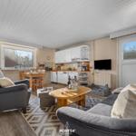 Wohn- und Küchenbereich mit Essplatz, Sofa, Sessel und TV.