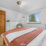 Schlafzimmer mit Bett, Fenster und Holztür.