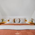 Schlafzimmer mit Bett, Nachttischen und Blumen.