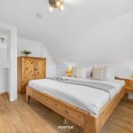 Schlafzimmer mit Holzbett, Nachttisch und Kleiderschrank.