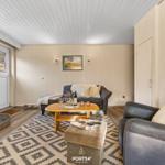 Wohnzimmer mit Sofa, Sessel, Couchtisch und Hund.