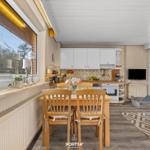 Küche mit Esstisch, Fenster und TV. Holzfußboden und weiße Schränke.