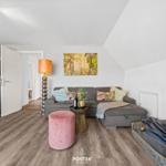 Wohn- und Küchenbereich mit Sofa, Kamin und Holzboden.