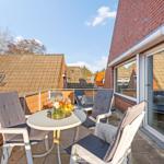 Terrasse mit Tisch, Stühlen und Blick auf Dächer.