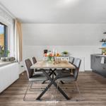 Essbereich mit Tisch und Stühlen, Küche mit Geräten und Fensterblick.