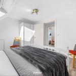 Schlafzimmer mit Dachschrägen, Bett, zwei Stühlen und Kleiderschrank.