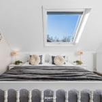 Dachgeschosszimmer mit Dachfenster, Bett und Sitzbank.