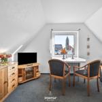 Dachgeschosszimmer mit TV, Schreibtisch und Fensterblick auf Kirchturm