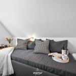 Doppelbett mit Kissen und Getränken unter schräger Decke