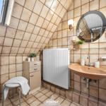 Badezimmer mit Dachschrägen, Waschbecken, Spiegel und Heizkörper.