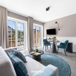 Wohnzimmer mit Sofa, Esstisch und Blick auf Balkon