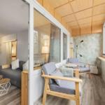 Wohnbereich mit Schlafsofa und Sitzbereich mit Fenstern und Holzdecke.