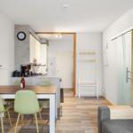 Wohnung mit Essbereich, Küche und Schlafzimmer. Holzfußboden und moderne Einrichtung.