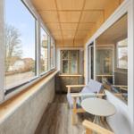 Terrasse mit Sitzgelegenheit und Blick auf Garten und Straße.