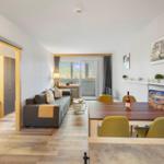 Wohnbereich mit Sofa, Esstisch und Balkontür.