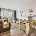 Wohn- und Essbereich mit Sofa, Esstisch und Balkontür.