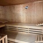 Sauna mit Holzbank und Temperaturmessgerät an der Wand.
