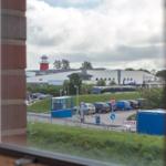 Aus dem Fenster ist ein roter Leuchtturm und ein Parkplatz mit Autos sichtbar.