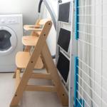 Wäschetrockner, Waschmaschine und hölzerner Kinderstuhl im Raum.