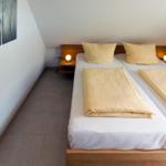 Zimmer mit Doppelbett, Holzgestell und zwei Nachttischen mit Lampen.