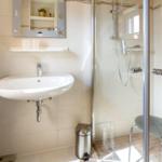 Badezimmer mit Dusche, Waschbecken und Spiegel