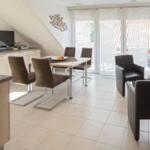 Küche, Essbereich und Wohnzimmer mit Tisch, Stühlen und TV.