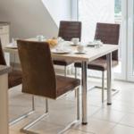 Essbereich mit Tisch und vier Stühlen, Küchenzeile und Glasfront.
