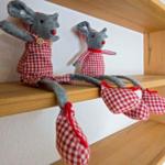 Zwei Stoffmäuse in karierten Kleidern sitzen auf einem Holzregal.