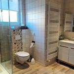 Badezimmer mit Wandheizkörper und Waschtisch, daneben der Treppenaufgang mit 3 Stufen und Geländer