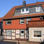 Haus mit rotem Dach und Holzverkleidung, Balkon und Fenster sichtbar.