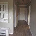 Flur mit Holzboden, weißen Türen und Wandregal aus Holzpaletten.